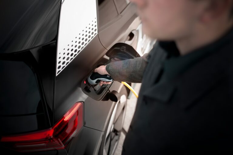 A technician inspects the undercarriage of a modern electric vehicle in a well-lit auto repair shop.