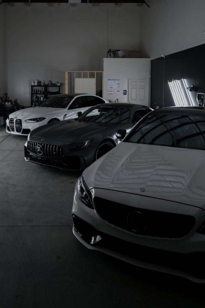 Technician inspecting a luxury vehicle on a lift with diagnostic equipment and tools nearby.